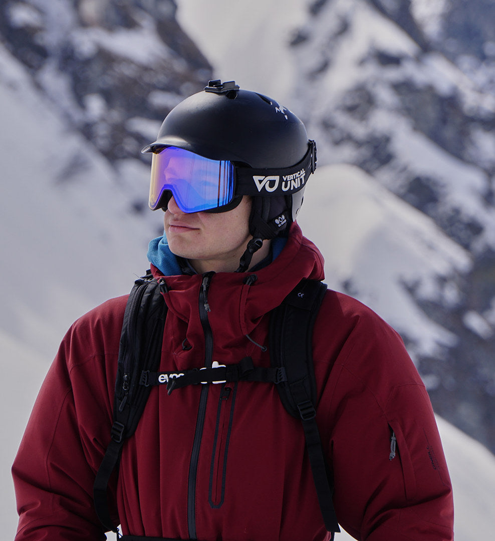 Skifahrer mit Helm trägt die Blaze 2.0 am verschneiten Berg; im verspiegelten Glas schimmert das Licht in Magenta und Blau